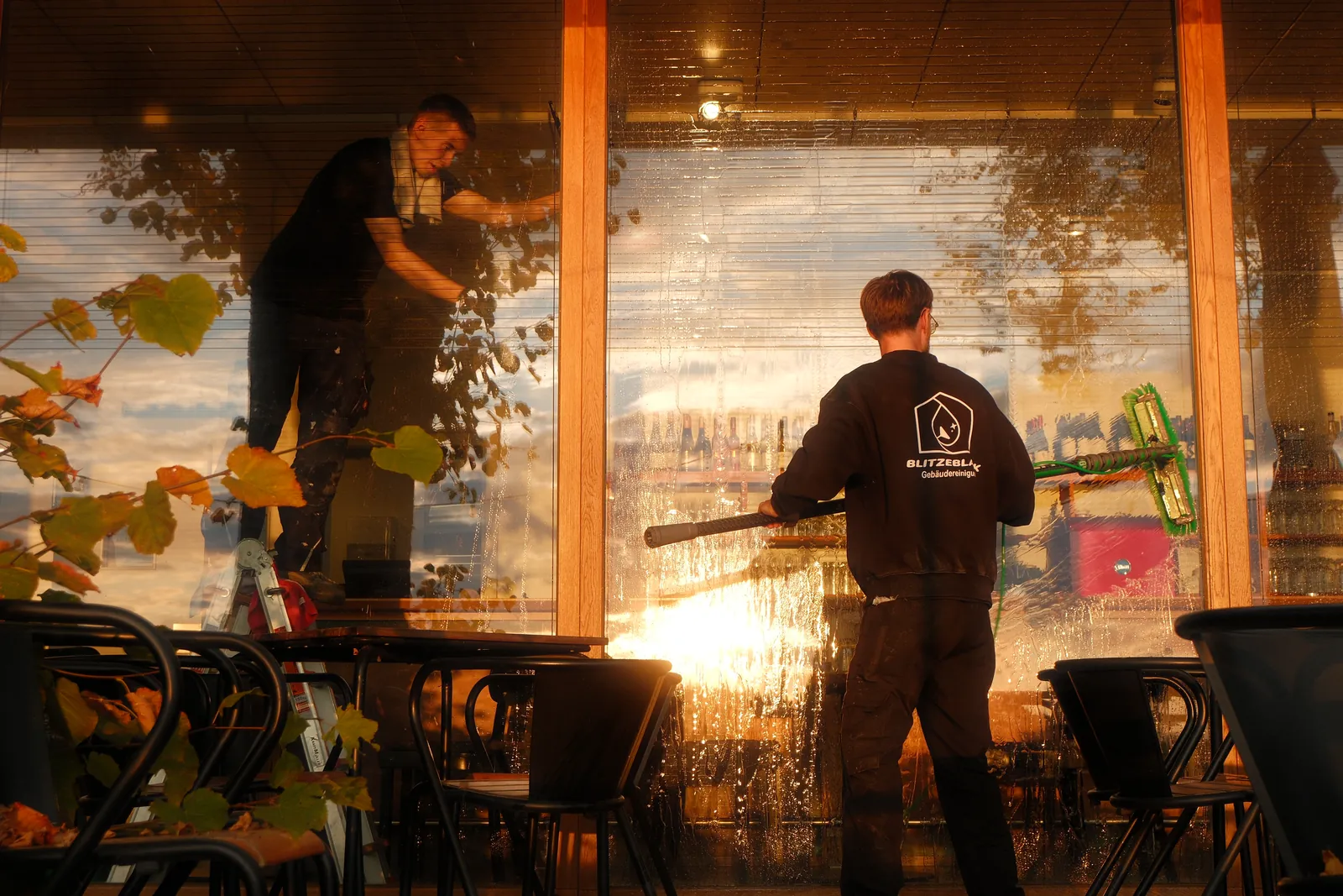 Streifenfreie Fensterreinigung in Lübeck – zwei BlitzeBlank Mitarbeiter reinigen die Schaufensterfront eines Restaurants
