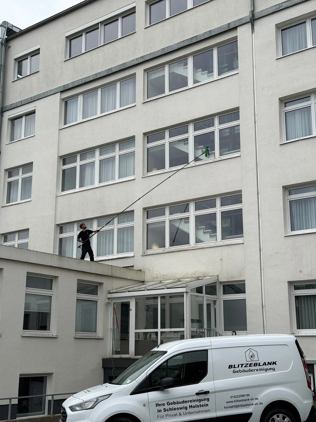 Glasfassadenreinigung in Lübeck – BlitzeBlank reinigt die Fensterfront eines mehrgeschossigen Bürogebäudes mit Teleskopstange