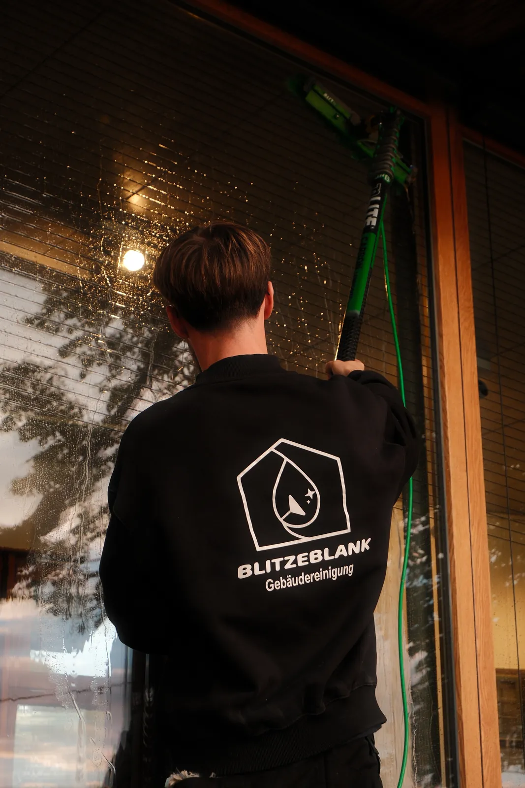 BlitzeBlank Mitarbeiter reinigt eine Glasfront mit Teleskopstange und Reinstwasser