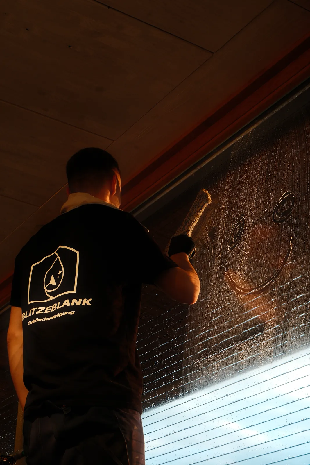 Schaufensterreinigung in Lübeck – BlitzeBlank Mitarbeiter reinigt eine große Fensterscheibe mit dem Wischer