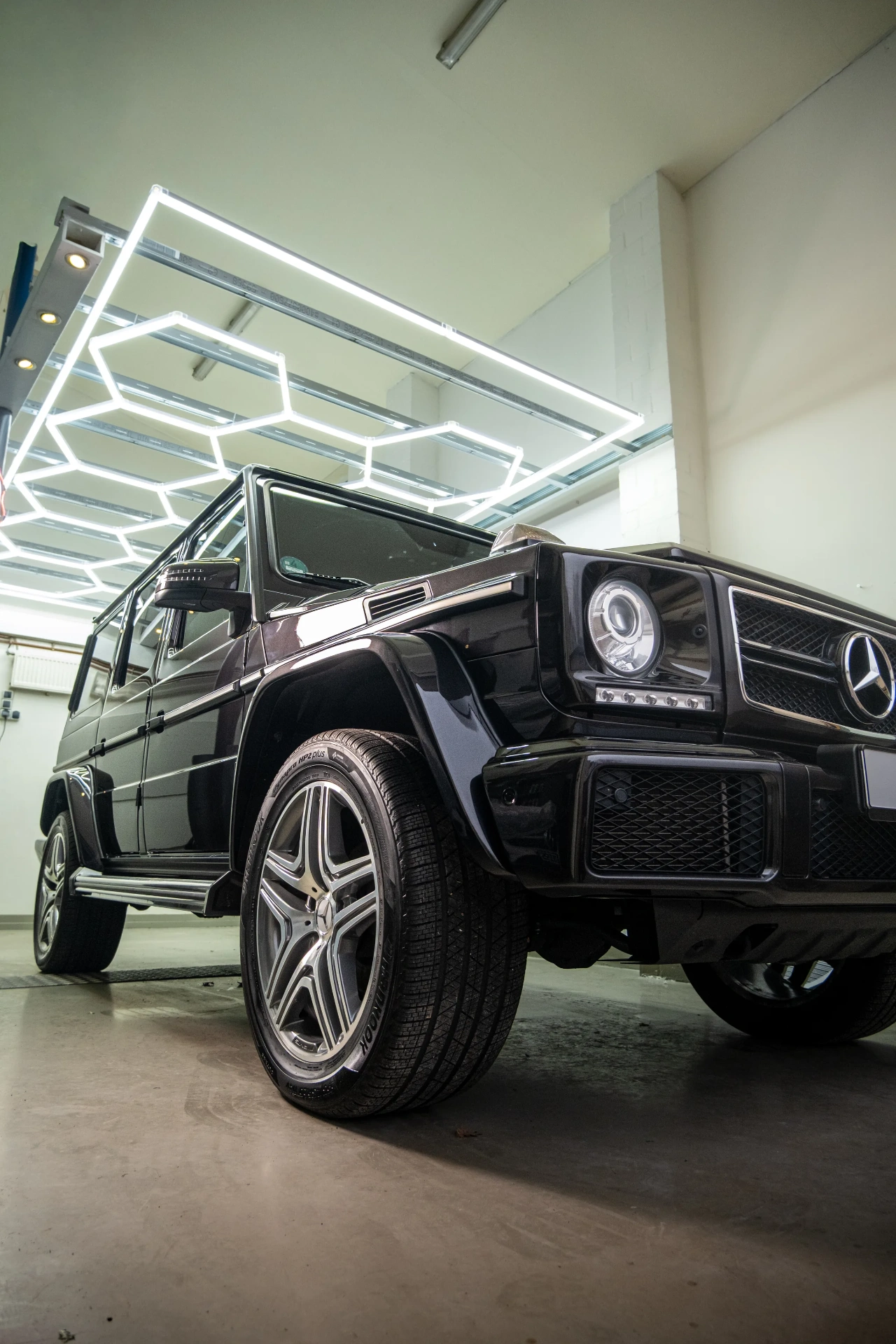 Mercedes G-Klasse schwarz in der Werkstatt unter Hexagon-Licht